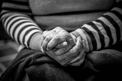 black and white close-up image of an elderly person sitting alone