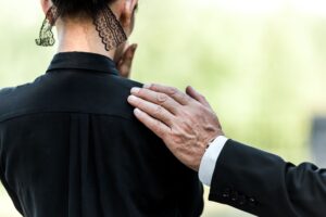 a woman grieving and a man patting her shoulders as an act of support